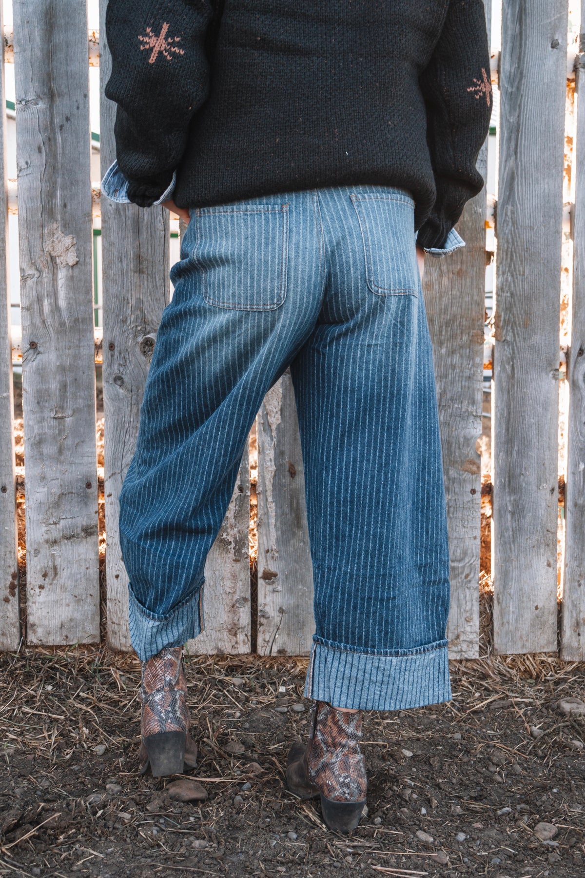 Back view of women's vintage wash pinstripe wide leg jeans featuring two back pockets, vertical stripes and oversized rolled denim cuffs.