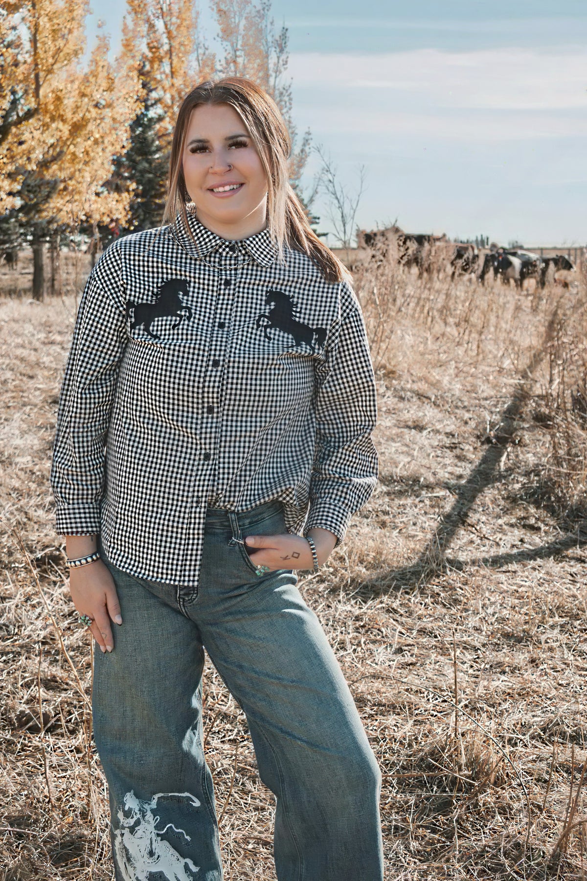 Black and white checkered western shirt with black horse graphics across the chest, paired with wide leg denim jeans.